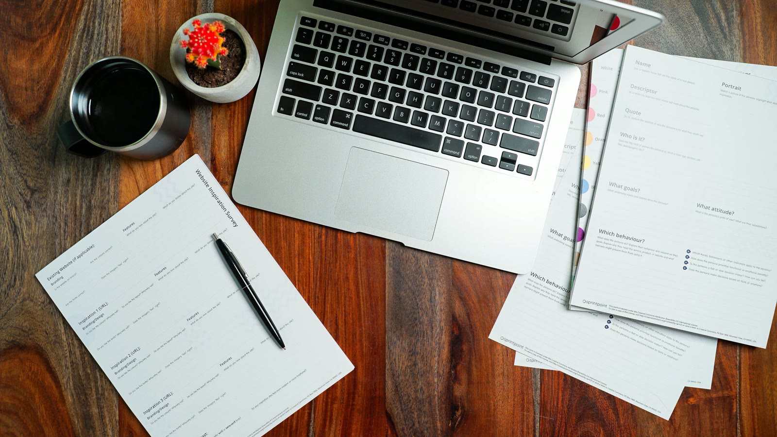 Overhead view of a desk with a laptop, career paperwork, a pen, and coffee